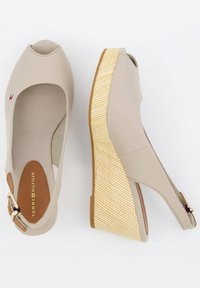 Sandales compensées beige à bout ouvert, talons compensés tissés, brides à la cheville avec boucles et marquage Tommy Hilfiger à l'intérieur de la semelle.
