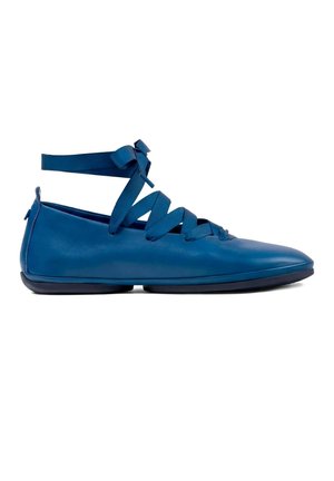 Scarpa bassa blu con punta appuntita e nastri incrociati alla caviglia su sfondo bianco.