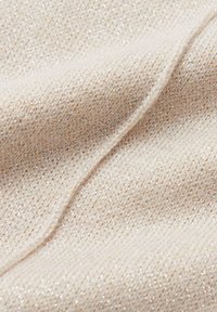 Tessuto beige con una superficie morbida e strutturata che presenta un leggero luccichio. Il tessuto mostra un fine motivo a maglia con dettagli intrecciati e una leggera elasticità.