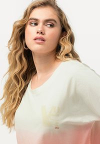 Koszulka z krótkim rękawem w jasnym zielonym kolorze z gradientowym wzorem przechodzącym w róż. Posiada wyblakłe logo i okrągły dekolt, wykonana z miękkiego materiału.