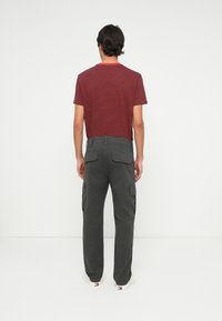 Rød og marineblå stripet kortermet T-skjorte sammen med grå cargo bukser med to sidelommer, flat midje og rett ben design.