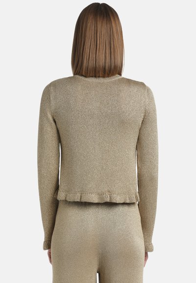 Trumpas auksinės spalvos blizgus megztinis, turintis apvalią iškirptę, ilgas rankoves ir smulkų kraštą. Audinys yra blizgantis, tekstūruotas.