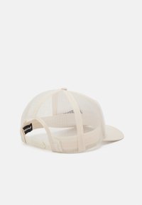 Beige hálós sapka ívelt napszemüvegű, állítható Snapback zárással és logó címkével a hátsó részen. A hálós kialakítás légáteresztőséget biztosít.