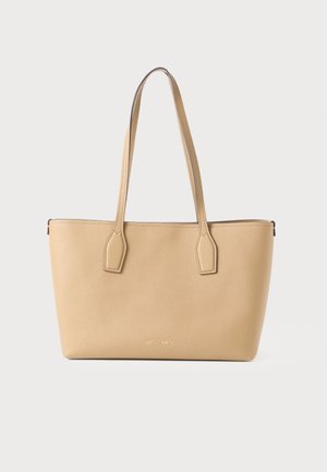 Sac cabas en cuir beige avec deux longues anses et coutures minimales, présenté sur un fond clair uni.