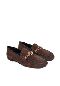 Brązowe zamszowe mokasyny z akcentem złotego łańcucha i czarnymi skórzanymi wykończeniami, z zaokrąglonym noskiem i płaską podeszwą.