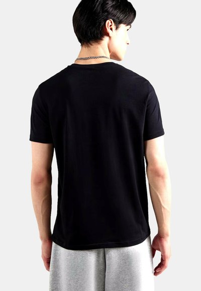 Maglietta nera in cotone con maniche corte e scollo rotondo, caratterizzata da una texture liscia e una vestibilità comoda, abbinata a pantaloncini grigi.