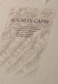 Tekst „Sogni di Capri” nad wierszem o starych piosenkach, wąskich uliczkach i Vespie pod zachodzącym słońcem na teksturowanym beżowym tle.