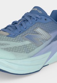 Baskets de sport bleu et bleu clair avec tige en mesh, col rembourré, lacets et logo à motif sur le côté.