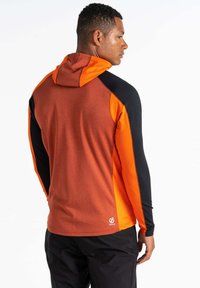 Kapuzenshirt in Orange, Schwarz und Rost; verfügt über kontrastierende Ärmel, strukturierter Stoff und eine taillierte Passform. Logo in der Nähe des Saums angebracht.