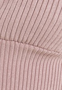 Ribbad tyg i mjuk rosa nyans, med växelvis upphöjda och sänkta ränder. Sömdetalj synlig längs den horisontella mittpunkten.