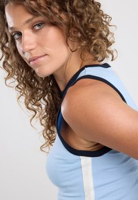 Light blue sleeveless top with navy trim, featuring a white vertical stripe on the side, made from smooth fabric with a fitted design.
