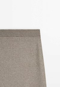 Partie supérieure d'une jupe en maille taupe avec une large ceinture élastique côtelée sur fond blanc.