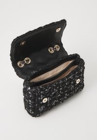 Clutch nera con paillettes e un'esterno texturizzato, hardware dorato e un interno foderato in tessuto con due compartimenti. Chiusura con bottoni a scatto.