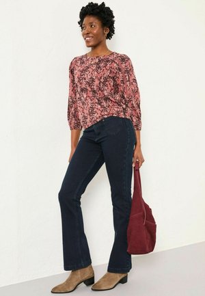 Floral patterned pink blouse with three-quarter sleeves, paired with dark blue flared jeans. Brown suede ankle boots and a burgundy bag.