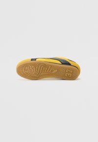 Sárga talpú, fekete felsőrészes Buffalo sneaker, struktúrált kidolgozással. A talp mintázott barázdákkal és logóval rendelkezik.