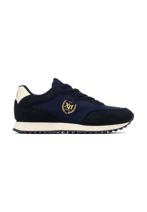 Zapatilla deportiva azul oscuro y negra con suela blanca y parche en el talón, logo de laurel dorado con texto en el lateral y suela texturizada para mejor agarre.