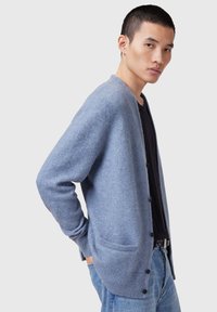 Cardigan azzurro chiaro realizzato in un morbido tessuto testurizzato. Presenta una vestibilità comoda, maniche lunghe e tasche frontali con bottoni neri.