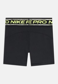 Shorts de sport noirs avec une taille élastique, arborant du texte "NIKE PRO" réfléchissant noir et jaune fluo. Design lisse et ajusté.