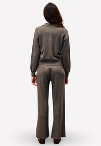 Pull en tricot marron et pantalon évasé assorti, présentant une coupe décontractée et une texture douce, avec une large ceinture et des poignets roulés.