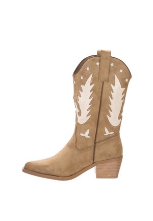 Botte de cowboy en daim marron avec des accents en cuir blanc, bout pointu, couture décorative et talon empilé. Présente des motifs découpés.