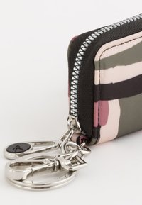 Cartera con cremallera en tela multicolor, con franjas negras, rosas, verdes y crema. Accesorios metálicos con un gancho para llaves.