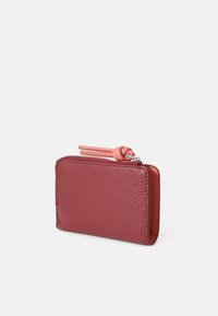 Portafoglio in pelle rossa con superficie texturizzata, chiusura a zip e linguetta in gomma rosa. Forma rettangolare compatta con angoli arrotondati.