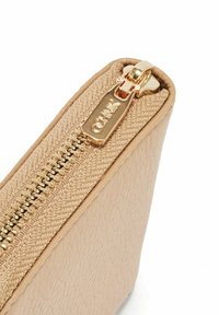 Beżowa skórzana saszetka z rogiem, na którym znajduje się złoty zamek z tkaninowym wykończeniem oraz suwak z grawerem "CEHNK".