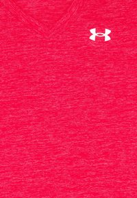 Camiseta de pico de color rojo jaspeado hecha de tela suave, con un logo blanco en la parte superior izquierda. Textura suave, diseño casual.