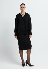 Black long-sleeve shirt with a subtle pattern, button-down front, paired with a fitted black pencil skirt and black high heels.