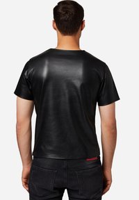 Schwarzes Kurzarm-T-Shirt aus glattem Leder, mit klassischem Rundhalsausschnitt und geradem Saum. Subtiler Glanz, keine Muster oder Grafiken.