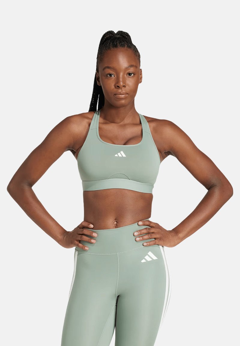 Reggiseno sportivo verde chiaro con una texture liscia, caratterizzato da una fascia di larghezza media e un logo con tre strisce bianche sul davanti.