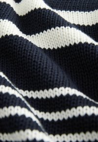 Dzianina w kolorze granatowym i kremowym w paski. Tekstura jest szorstka, z grubym splotem, podkreślająca kontrastujące kolory.