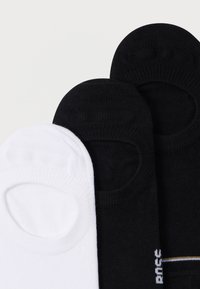 Tri páry ponožiek: jeden pár bielych a dva čierne s rebrovanou textúrou, členková dĺžka, s logom a jemným pruhom na čiernych pároch.