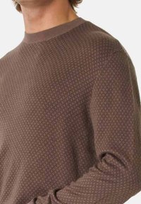 Maglione marrone lavorato a maglia con un design testurizzato, dotato di un collo rotondo e maniche lunghe. Il materiale presenta un motivo sottile per un tocco di dettaglio in più.
