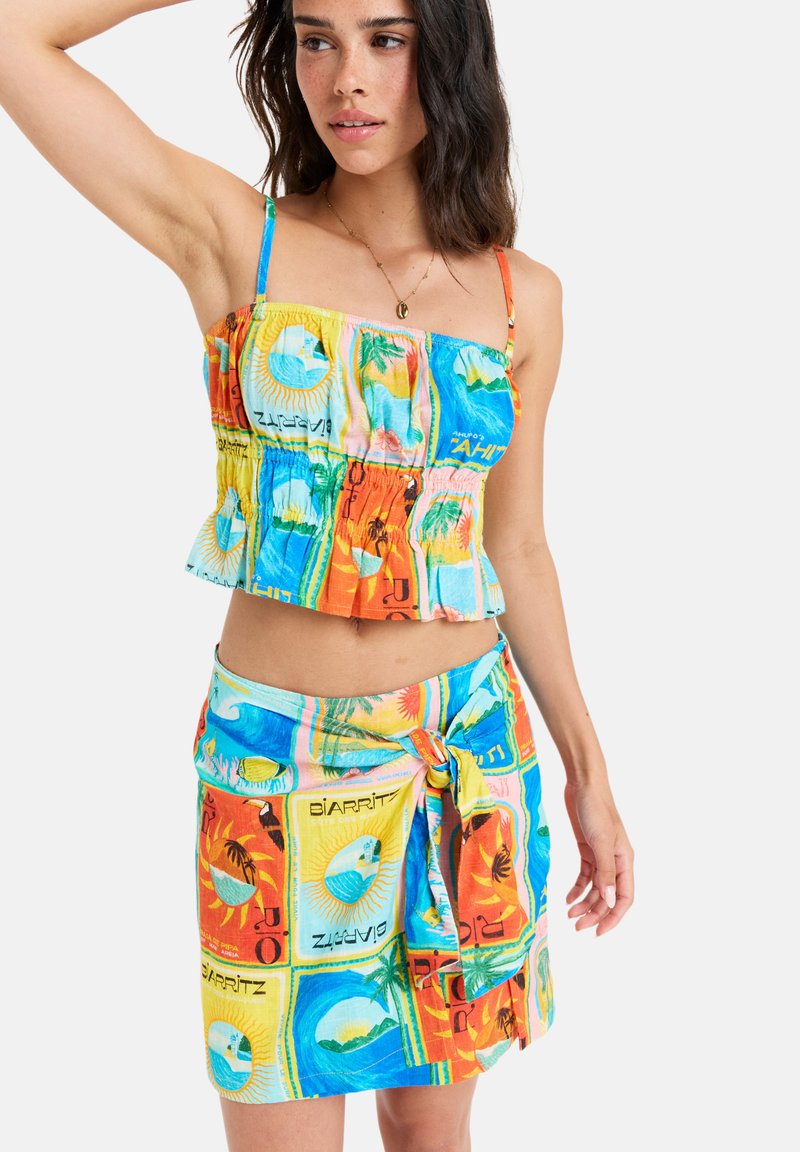 Conjunto colorido de dos piezas que incluye un top corto con tirantes finos y una falda envolvente a juego. Hecho de una tela ligera y estampada con motivos tropicales.