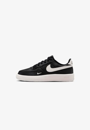 Mustat matalat Nike-tennarit valkoisella pohjalla ja valkoisella Swoosh-logolla, kuvioitu nahkapäällinen sekä mustat nauhat, nähtynä sivulta.