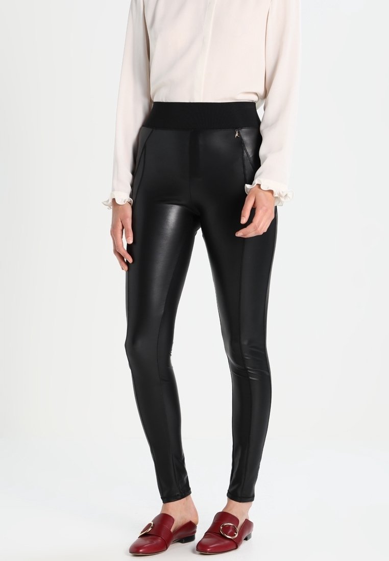 Leggings en simili cuir noir avec une taille élastique haute, dotés de poches latérales zippées et d'une texture lisse et brillante.