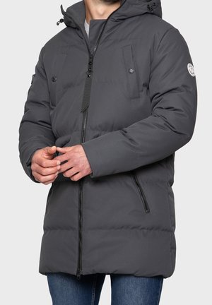 Veste matelassée grise avec capuche, dotée de poches latérales zippées et de poches poitrine à boutons-pression, fabriquée en matériau lisse et résistant à l'eau.