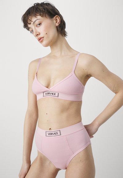 Rózsaszín bordázott bralette és magas derekú alsónemű szett állítható pántokkal és logó részletekkel. Sima textúra, minimális dizájn és varrás nélküli kivitel.