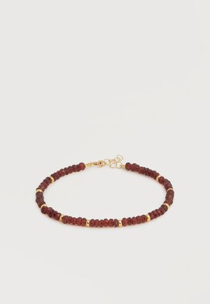 Pulsera de cuentas con pequeñas piedras redondas de color rojo oscuro separadas por cuentas espaciadoras doradas y un cierre dorado sobre un fondo blanco.