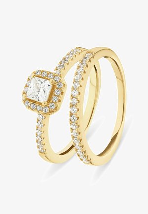 Goldring-Set mit einem quadratischen, princess-cut Mittelpunktstein, umgeben von kleineren Steinen entlang des Bandes, das eine polierte Oberfläche zeigt.