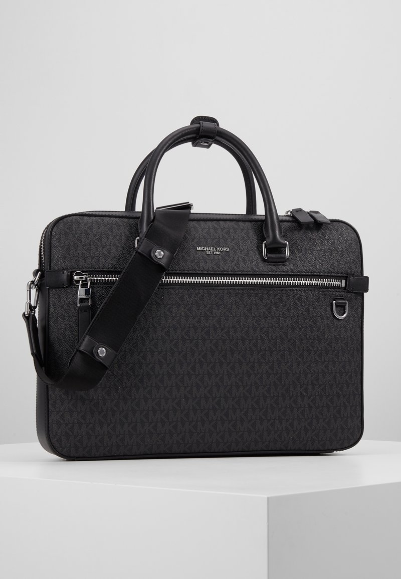 Mallette noire Michael Kors avec doubles poignées, poche avant zippée, bandoulière ajustable et motif de logo ton sur ton sur la surface.