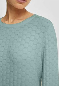 Licht teal sweater met een structuur van bolletjespatroon, ronde halslijn en geribbelde manchetten. Zachte gebreide stof, aansluitende pasvorm.