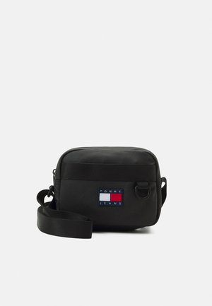 Sort skuldertaske med rektangulært form. Fremstillet af slidstærkt stof, med et logo-patch i rød, hvid og blå samt en justerbar rem.