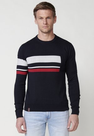 Suéter azul marino con rayas horizontales en gris, blanco y rojo. Fabricado en un tejido de punto suave con puños y dobladillo acanalados.