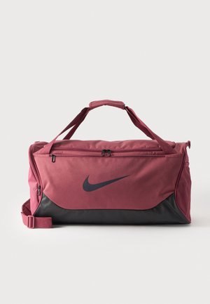 Дъфел чанта Nike в розово и цвят антрацит, с горни дръжки, презрамка за рамо, джобове с цип и страничен мрежест джоб, показана на изчистен фон.
