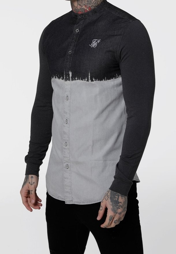 Camicia a maniche lunghe con chiusura a bottoni, caratterizzata da un upper in denim nero e un lower in tessuto grigio. Corpo testurizzato con un sottile effetto sfumato.