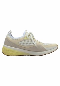 Zapatilla deportiva beige con parte superior de malla, acentos blancos, cordones planos y plantilla amarilla texturizada. Suela de goma con tacos para mayor agarre.