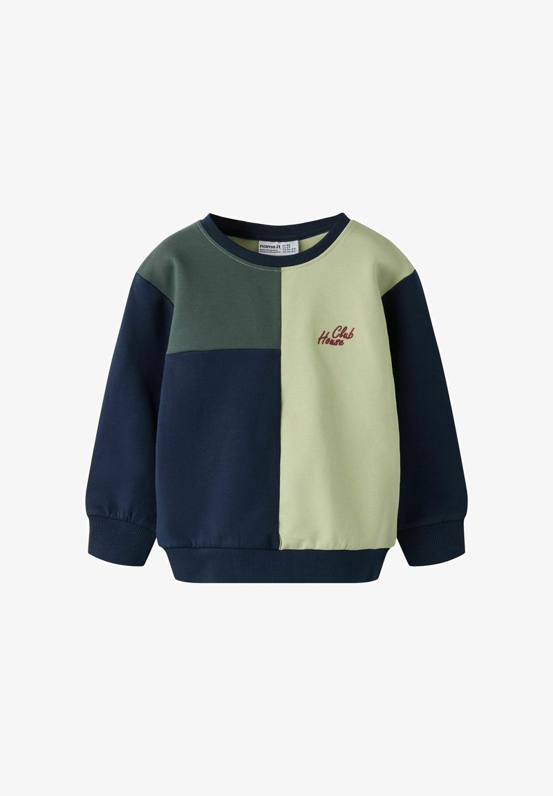 Fargablokkert genser i marineblå, grønn og lys gul. Har ribbede mansjetter og krage med brodert "Club House" i rødt.