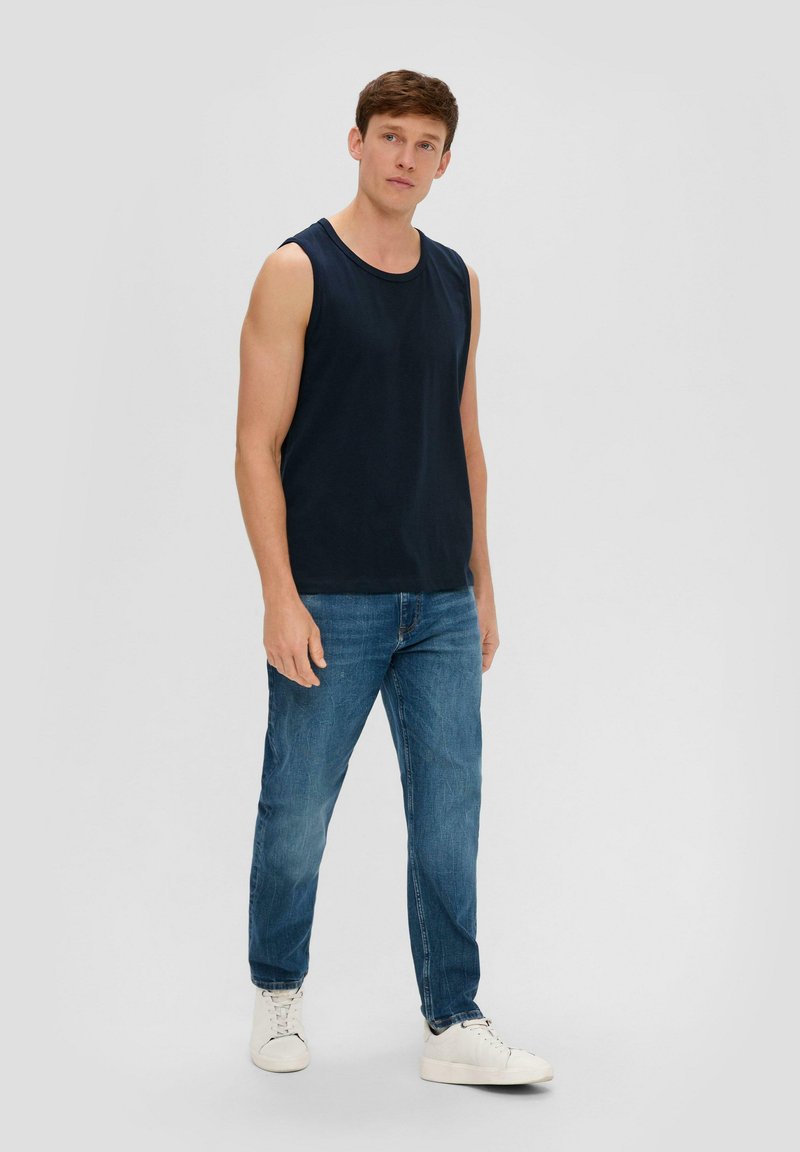 Marineblaues Baumwoll-Top mit Rundhalsausschnitt, kombiniert mit hellblauen Jeans und weißen Sneakers. Sanfte Textur, ärmelloses Design.